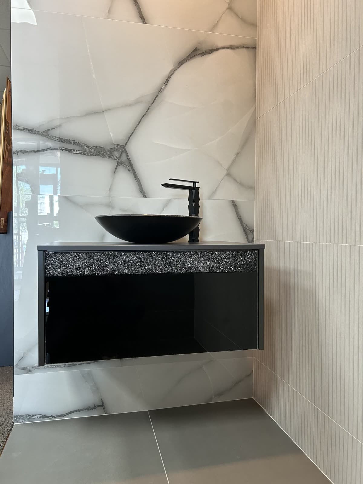 Bathroom with black floating vanity, vessel sink and marble walls