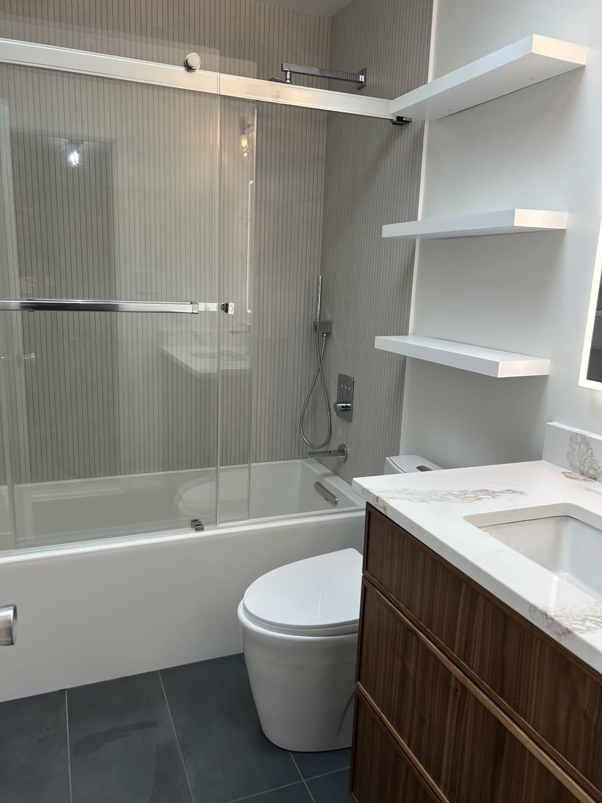Bathroom with soaking tub, fluted tile surround and wood vanity