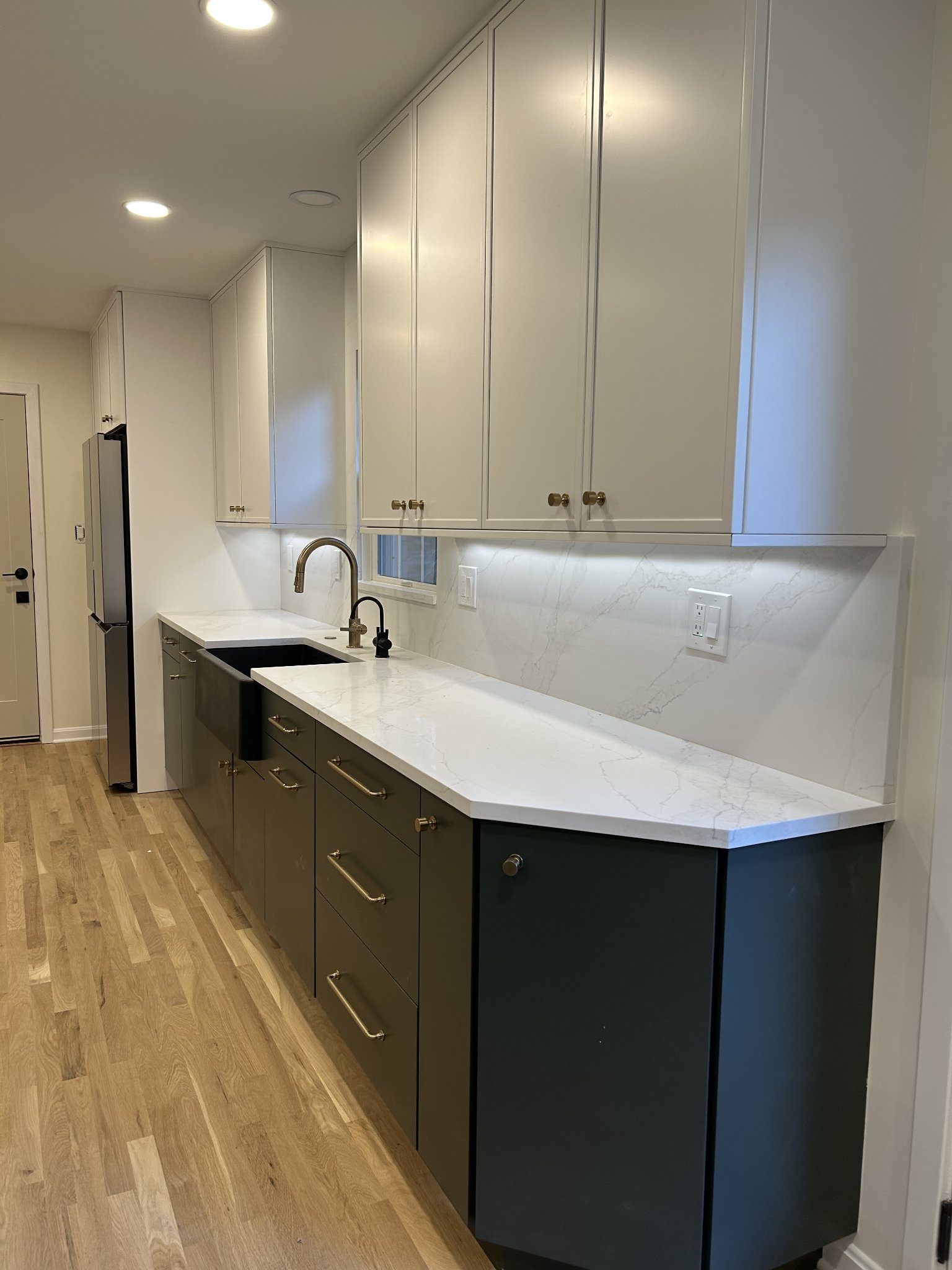 Kitchen remodel with dark green cabinetry and marble counters