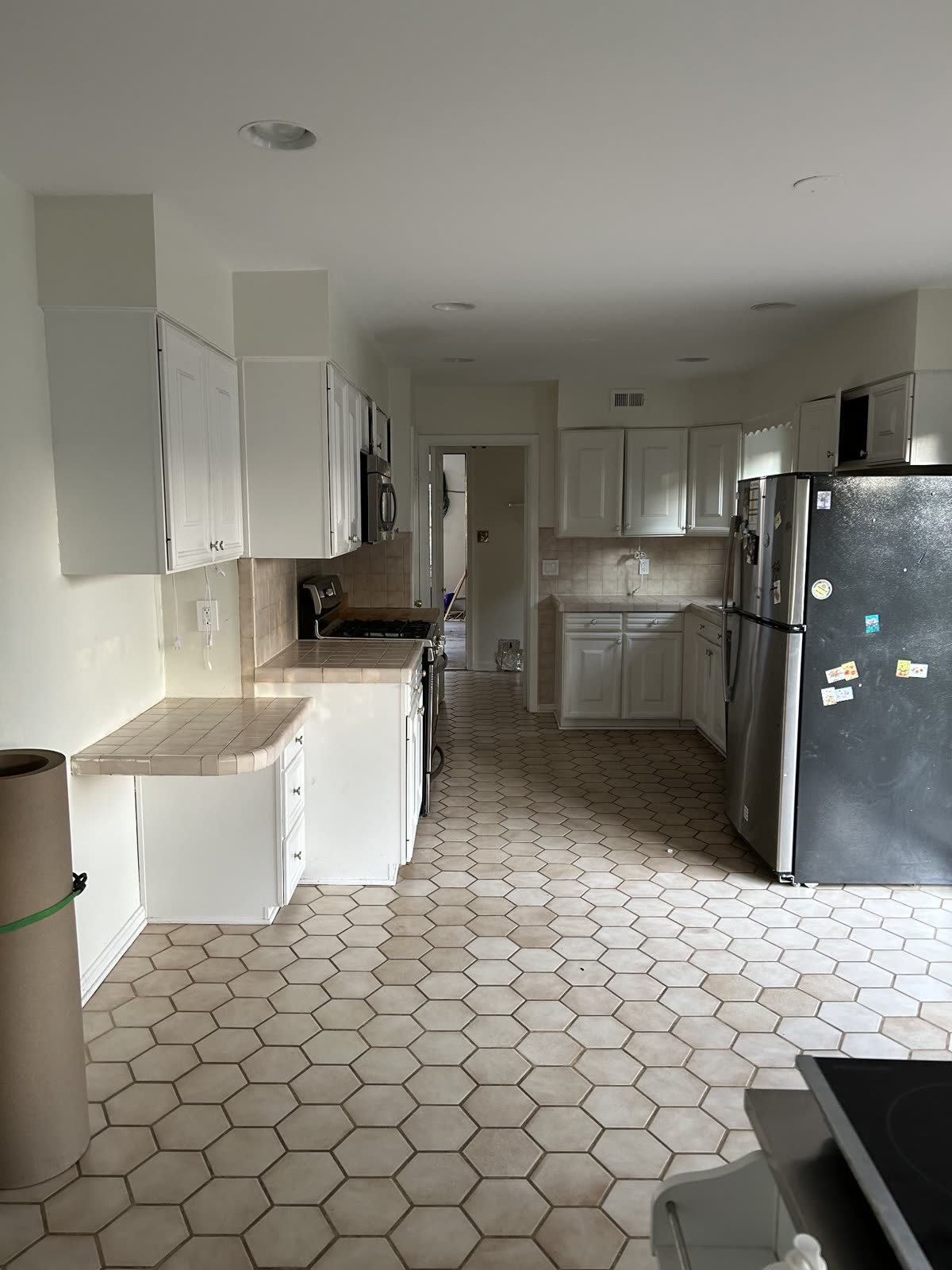 Kitchen before remodel with dated hexagon tile flooring and worn cabinets