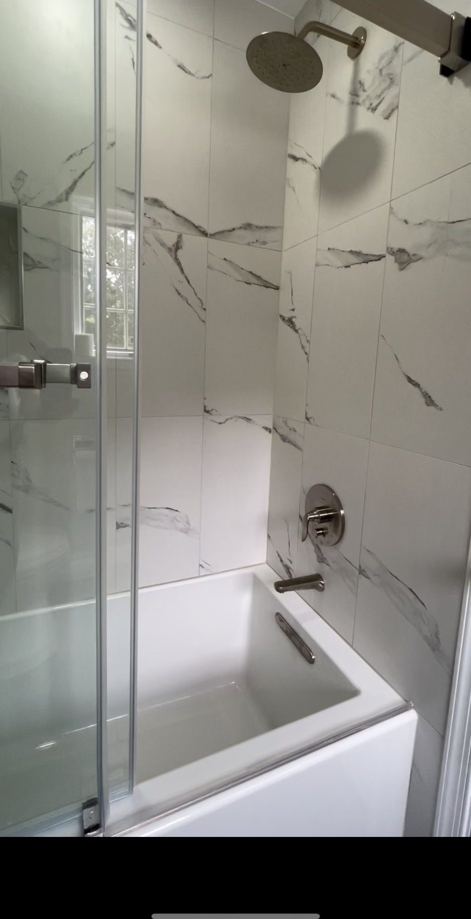 Tub and shower combination with marble-look tile and glass door