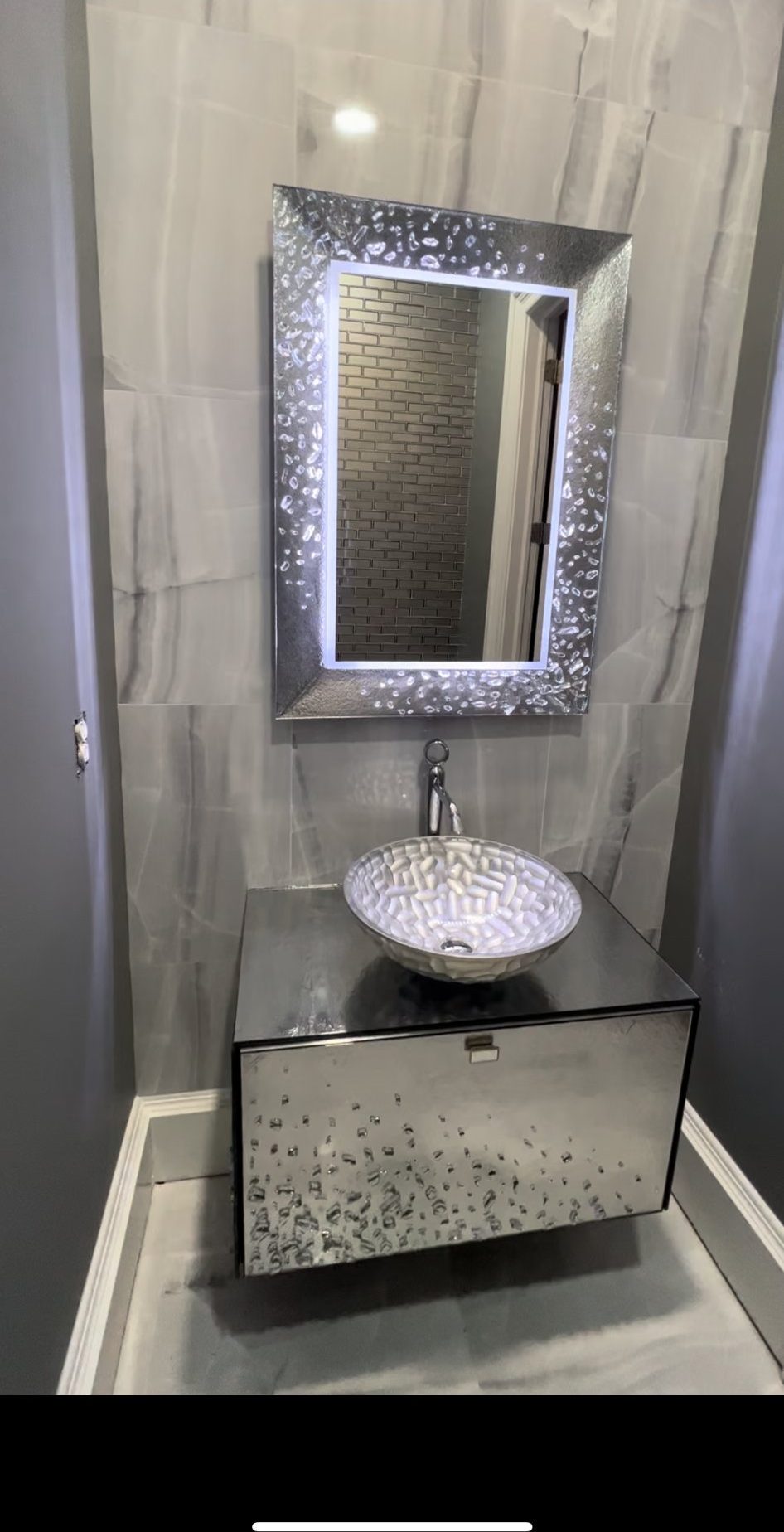 Powder room with vessel sink vanity and backlit decorative mirror