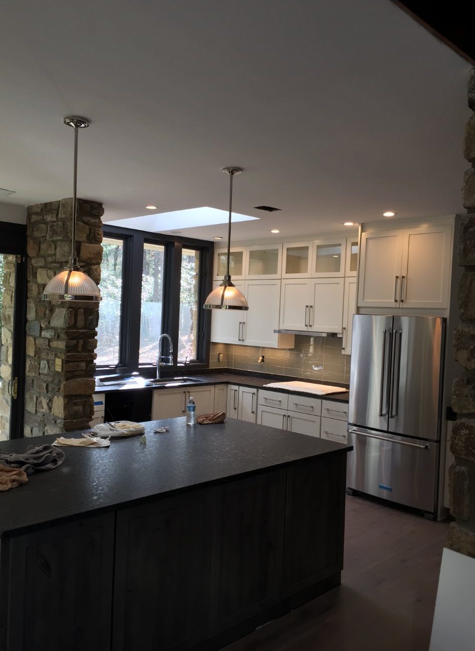 Kitchen remodel with dark island, stone columns and skylight