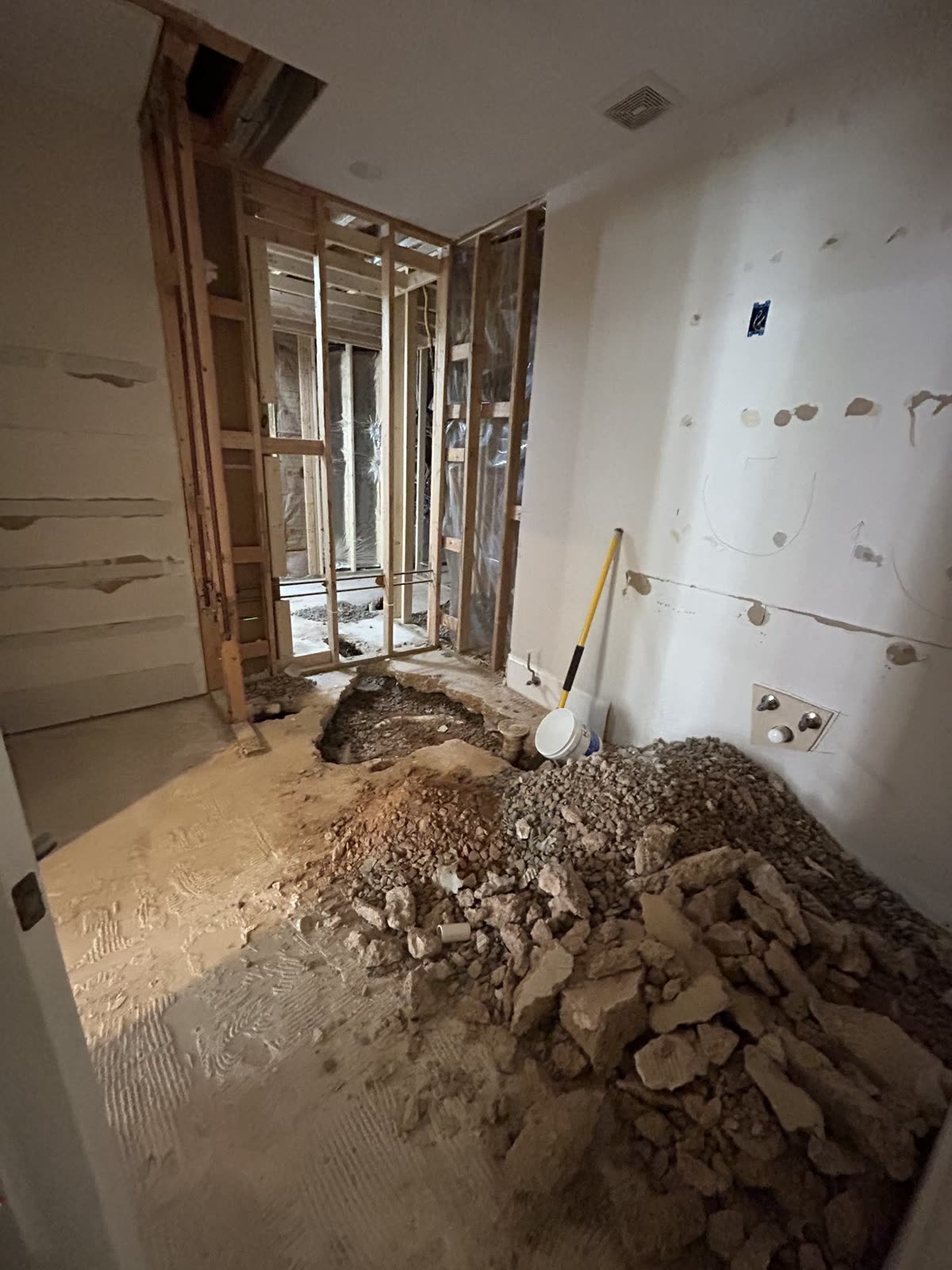 Bathroom demolition in progress with rubble and exposed framing